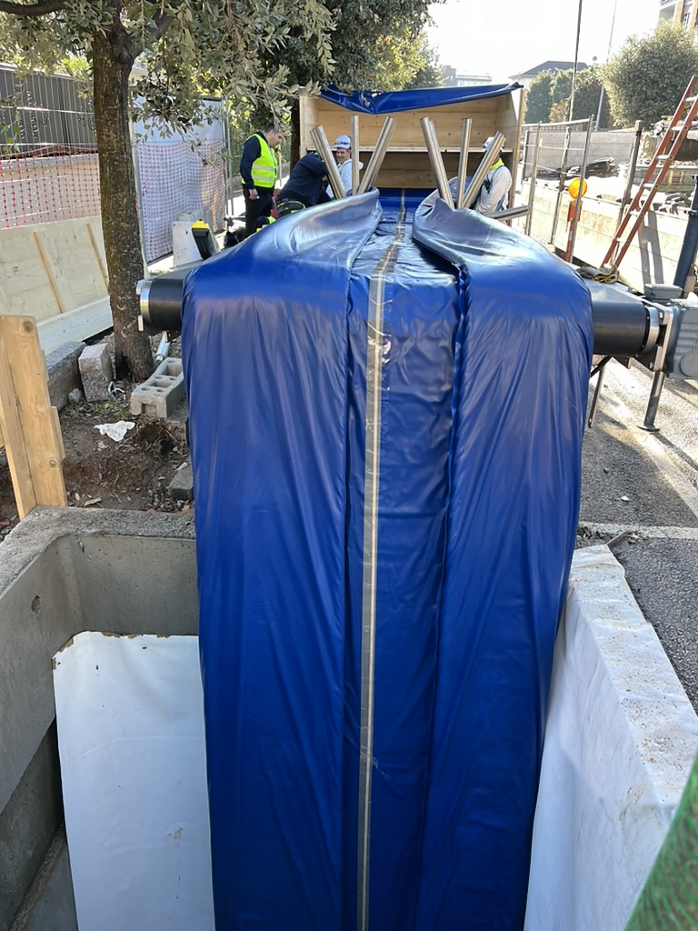 Liner blu guidato dai rulli verso lo scavo durante l’inserimento CIPP UV